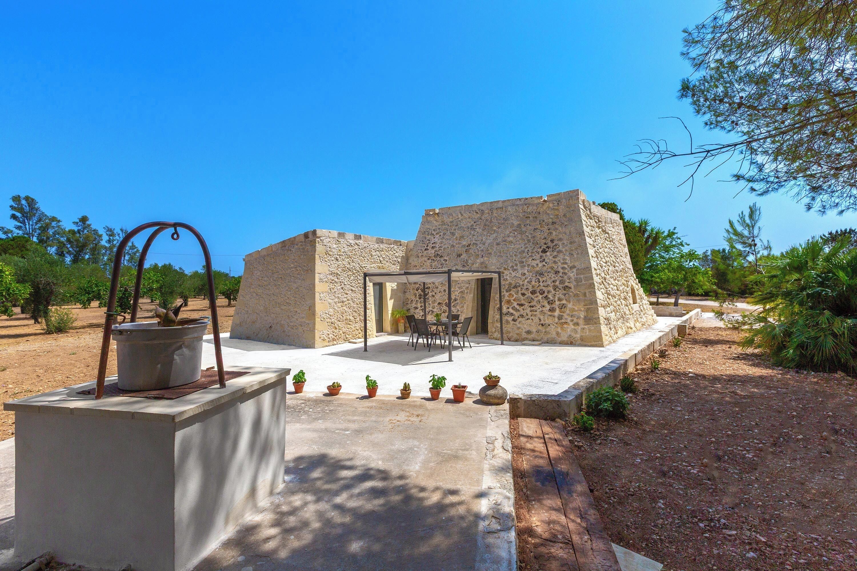 A stone building with a patio area, a table, and potted plants.