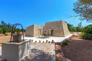 A stone building with a patio area, a table, and potted plants. - Pajara Donna Piccinni by BarbarHouse (Carpignano Salentino)