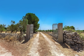 A rural road leading to a gated entrance with stone walls on either side. - Pajara Donna Piccinni by BarbarHouse (Carpignano Salentino)