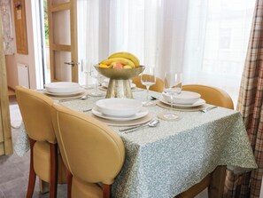 A dining table set with white plates, silverware, and a fruit bowl. - The Manors Retreat (Dunbar)