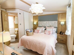 A bedroom with a bed, bedside tables, a lamp, a wall-mounted light, and a window with curtains. - The Manors Retreat (Dunbar)