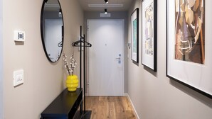 A hallway with a mirror, a yellow vase with branches, a coat rack, and framed artwork on the walls. - Gallo Studio  by BarbarHouse (Bari)
