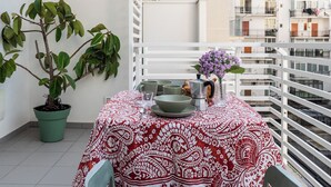 A balcony with a table set for two, a potted plant, and a view of the surrounding buildings. - Gallo Studio  by BarbarHouse (Bari)