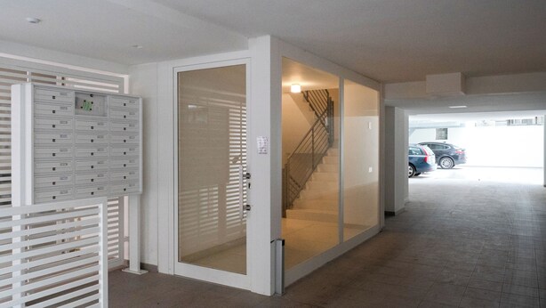 A hallway with a mail slot, a glass door, and a staircase leading to a parking area. - Gallo Studio  by BarbarHouse (Bari)