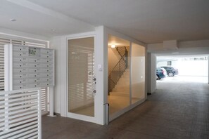 A hallway with a mail slot, a glass door, and a staircase leading to a parking area. - Gallo Studio  by BarbarHouse (Bari)