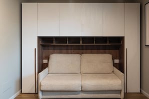 A room with a built-in seating area featuring a cushioned bench and a wooden panel above. - Gallo Studio  by BarbarHouse (Bari)