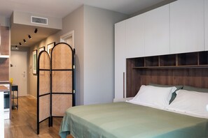 A bedroom with a bed, a wardrobe, a partition, and a small table.