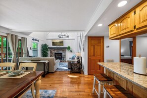A spacious living area with a fireplace, wooden flooring, and a dining area with a table and chairs. - New! Hot Tub/Game Room-Close to Dollywood (Pigeon Forge)