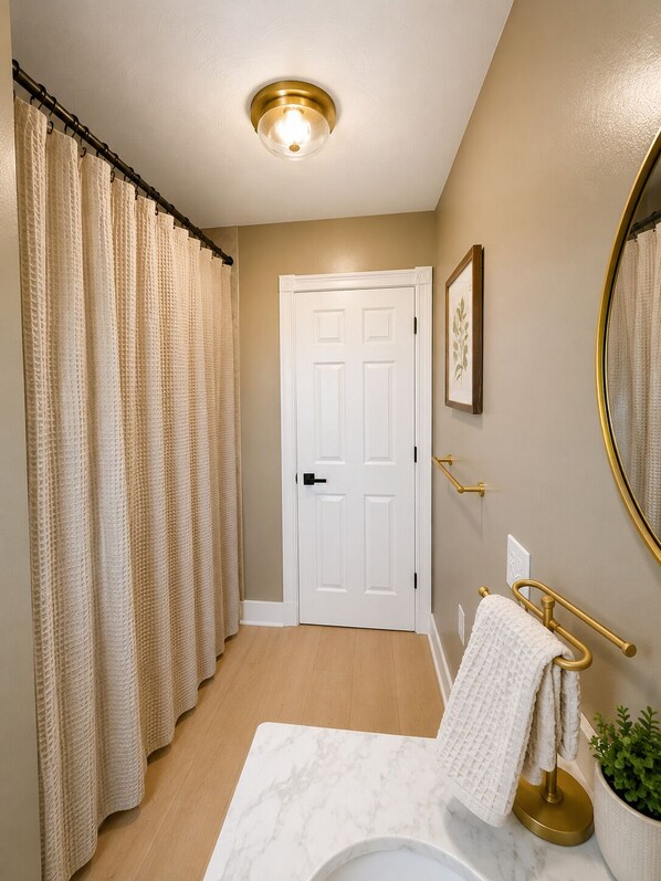 Une salle de bain avec une porte blanche, un porte-serviettes avec une serviette, une plante en pot et un miroir.