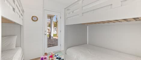 Un dormitorio infantil con literas, una puerta que da al exterior y juguetes en el suelo.