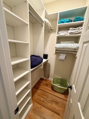 Un dressing accessible sans porte, doté d’étagères ouvertes, d’une tringle et d’un lit escamotable.