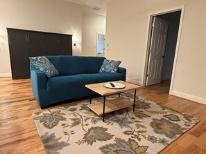 Un salon avec un canapé bleu, une table basse en bois et un tapis à motifs floraux.