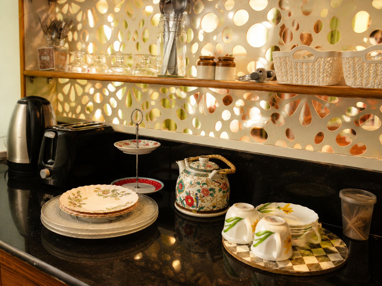 A kitchen counter with a coffee maker, toaster, tea set, and decorative plates.