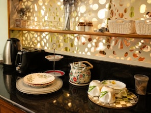A kitchen counter with a coffee maker, toaster, tea set, and decorative plates.