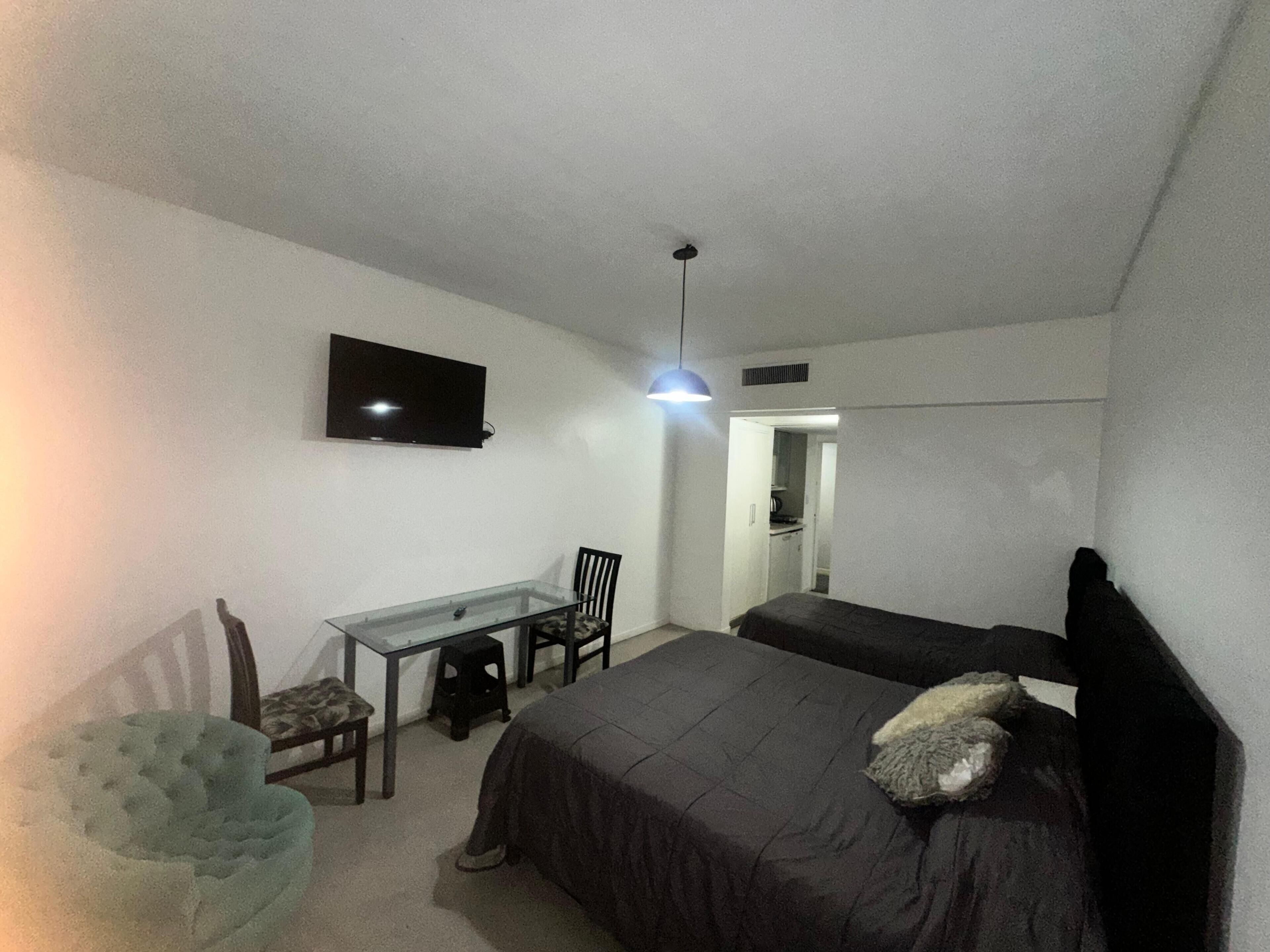 Une chambre à coucher avec un lit, un bureau, une chaise, une télévision et une petite table.