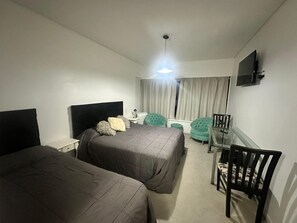A hotel room with two beds, a desk, a chair, and a TV on the wall. - Apartment 7/707 (Buenos Aires)