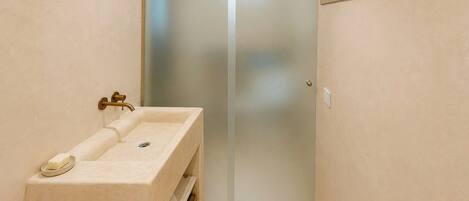 A bathroom with a sink, a mirror, and a door leading to another room.