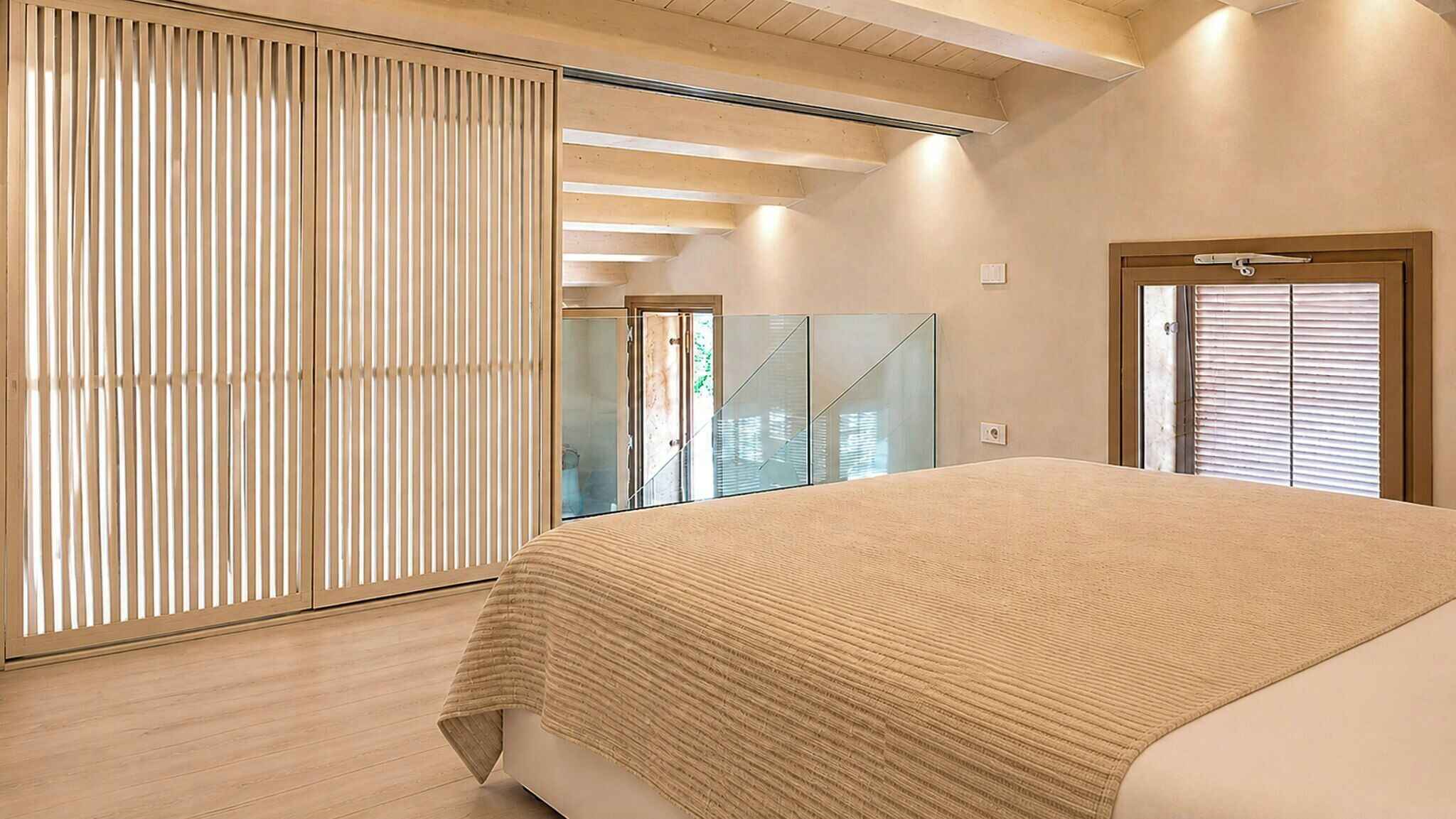 Een slaapkamer met een groot bed, een schuifdeur en uitzicht op een trap.