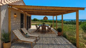 A covered outdoor patio with a table and chairs, a pergola, and a view of the sea. - Restored cottage with views over Vendicari (Noto)