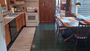Una cocina con armarios de madera, una estufa y un comedor con mesa y sillas.