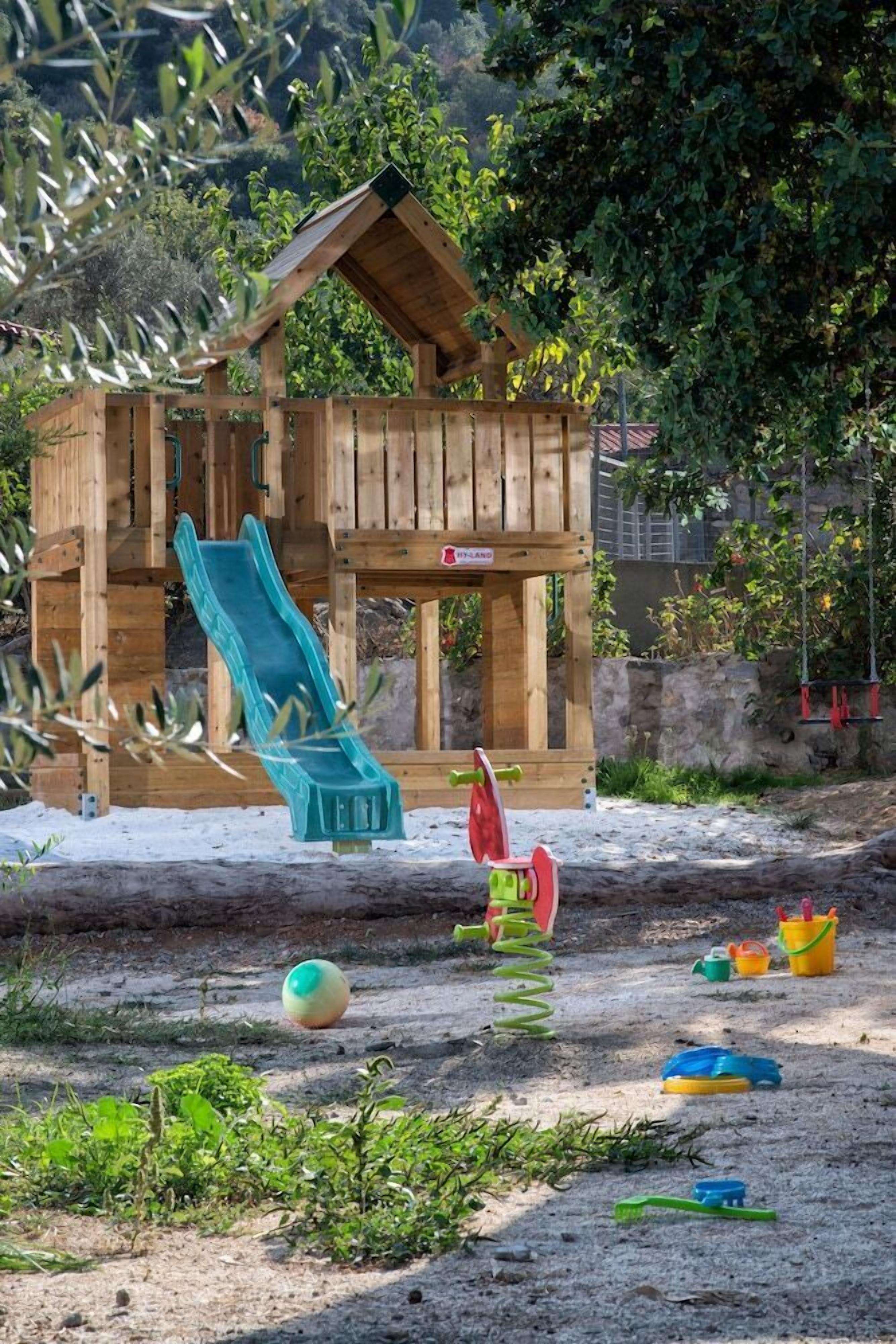 Una casita de juegos de madera con un tobogán y un columpio.