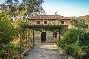 A stone building with a tiled roof, a wooden pergola, and a sign indicating a reception area. - Enagron Ecotourism Village (Mylopotamos)