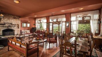 Un salón amplio con chimenea, varias zonas de estar y ventanas grandes.