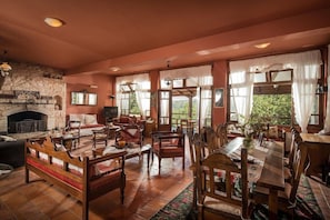Un salón amplio con chimenea, varias zonas de estar y ventanas grandes.