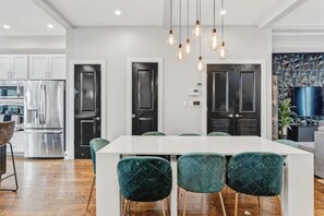 A modern kitchen with a white island, dark doors, and hanging pendant lights. - Pillar&Peak Modern NoMa 3BR| Rooftop Deck +Parking (Washington)