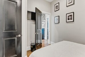 Ein Schlafzimmer mit einem Bett, einem Kleiderschrank und einer Tür zu einem Flur mit einer Treppe.