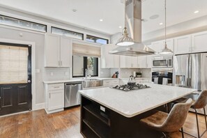 A modern kitchen with a central island, stainless steel appliances, and a large window. - Pillar&Peak Modern NoMa 3BR| Rooftop Deck +Parking (Washington)
