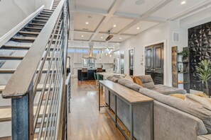 A modern interior with a staircase, a kitchen area, and a seating area with a sofa and a coffee table. - Pillar&Peak Modern NoMa 3BR| Rooftop Deck +Parking (Washington)