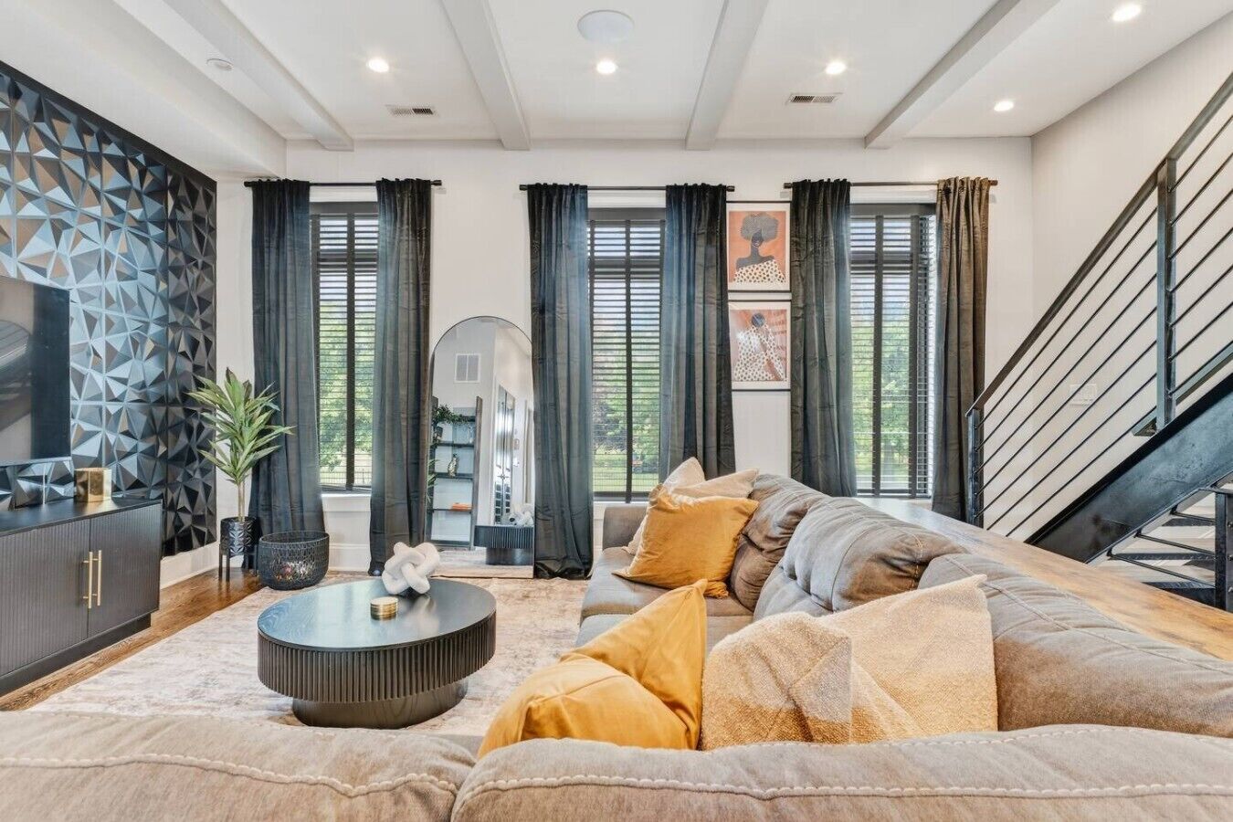 A modern living room with a sectional sofa, a round coffee table, and a decorative wall panel.