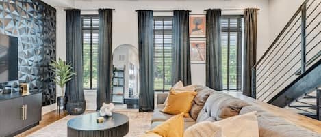 A modern living room with a sectional sofa, a round coffee table, and a decorative wall panel.