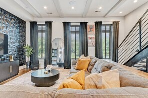 Ein modernes Wohnzimmer mit einer Eckcouch, einem runden Couchtisch und einer dekorativen Wandverkleidung.