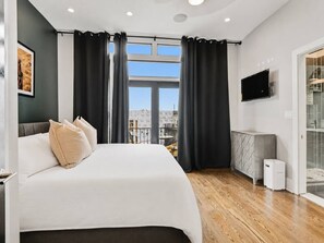 Ein modernes Schlafzimmer mit einem großen Bett, einem Fernseher und Blick auf die Stadt.