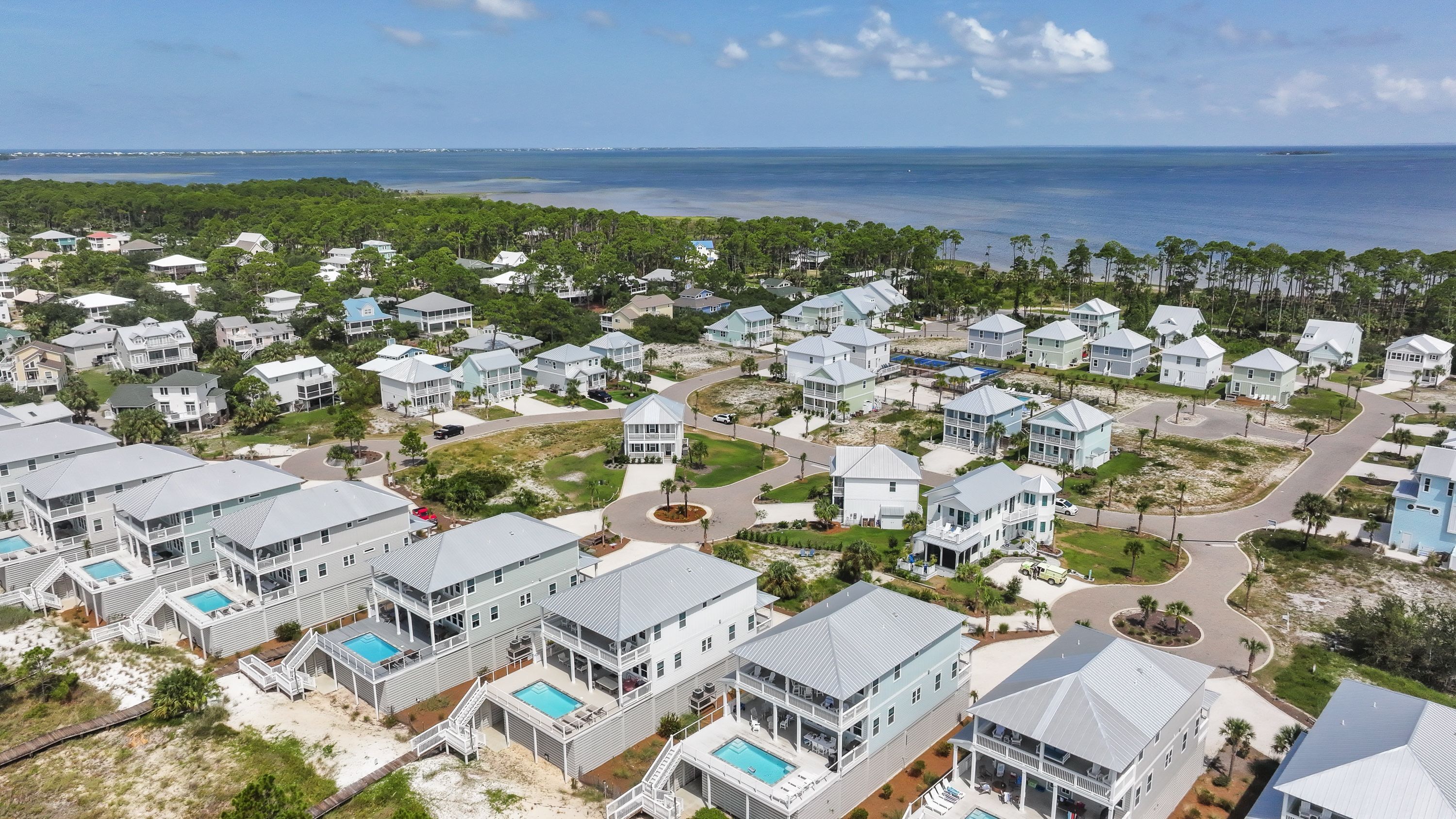 Una zona residencial costera con varias casas de dos pisos, algunas con terrazas y piscinas.