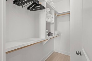 A white closet with shelves, a hanging rod, and a wooden floor. - Pet-Friendly Beach House with Ocean Views (Port St. Joe)