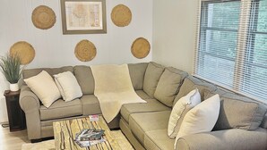 A living room with a sectional sofa, a wooden coffee table, a ceiling fan, and decorative wall hangings. - Relaxing lake front property with kayak/paddleboard. (Martin)