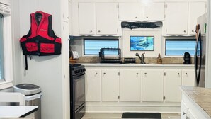 A modern kitchen with white cabinets, a stainless steel stove, and a black refrigerator. - Relaxing lake front property with kayak/paddleboard. (Martin)