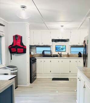A modern kitchen with white cabinets, a stainless steel stove, and a black refrigerator. - Relaxing lake front property with kayak/paddleboard. (Martin)