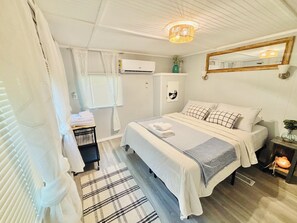 A bedroom with a bed, a bedside table, a mirror, a window with blinds, an air conditioning unit, and a ceiling light fixture. - Relaxing lake front property with kayak/paddleboard. (Martin)