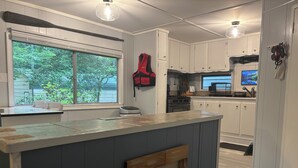 A kitchen with a central island, white cabinets, a window with a view of greenery, and a welcome sign. - Relaxing lake front property with kayak/paddleboard. (Martin)