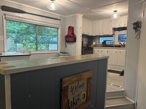 A kitchen with a central island, white cabinets, a window with a view of greenery, and a welcome sign. - Relaxing lake front property with kayak/paddleboard. (Martin)