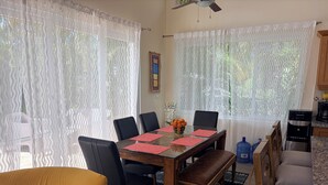A dining area with a wooden table, black chairs, and a bench. There is a water dispenser and a blue water container on the counter. - Breezy, Beautiful 2 Bedroom Caribbean Villa! (Sosúa)