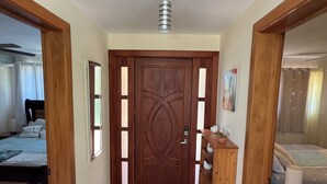 A hallway with a wooden door, a ceiling fan, and a bed with a patterned bedspread. - Breezy, Beautiful 2 Bedroom Caribbean Villa! (Sosúa)