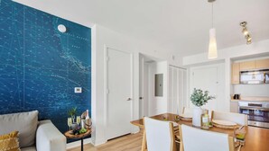 A modern kitchen with stainless steel appliances, a dining area with a wooden table, and a large blue wall with nautical charts. - Beautiful 1BR - Intracoastal View & Fitness Center (Hallandale Beach)
