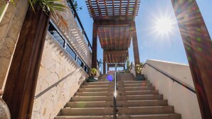 A staircase leading to a covered area with a pergola, surrounded by stone walls and potted plants. - Beautiful 1BR - Intracoastal View & Fitness Center (Hallandale Beach)