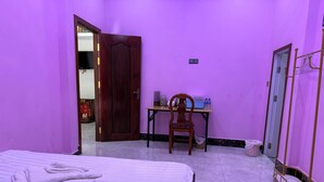 A room with a bed, a desk, a chair, a mirror, and a wardrobe. - Bun homestay  (Battambang)