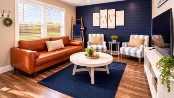 A living room with a brown leather sofa, a round coffee table, and two striped armchairs.